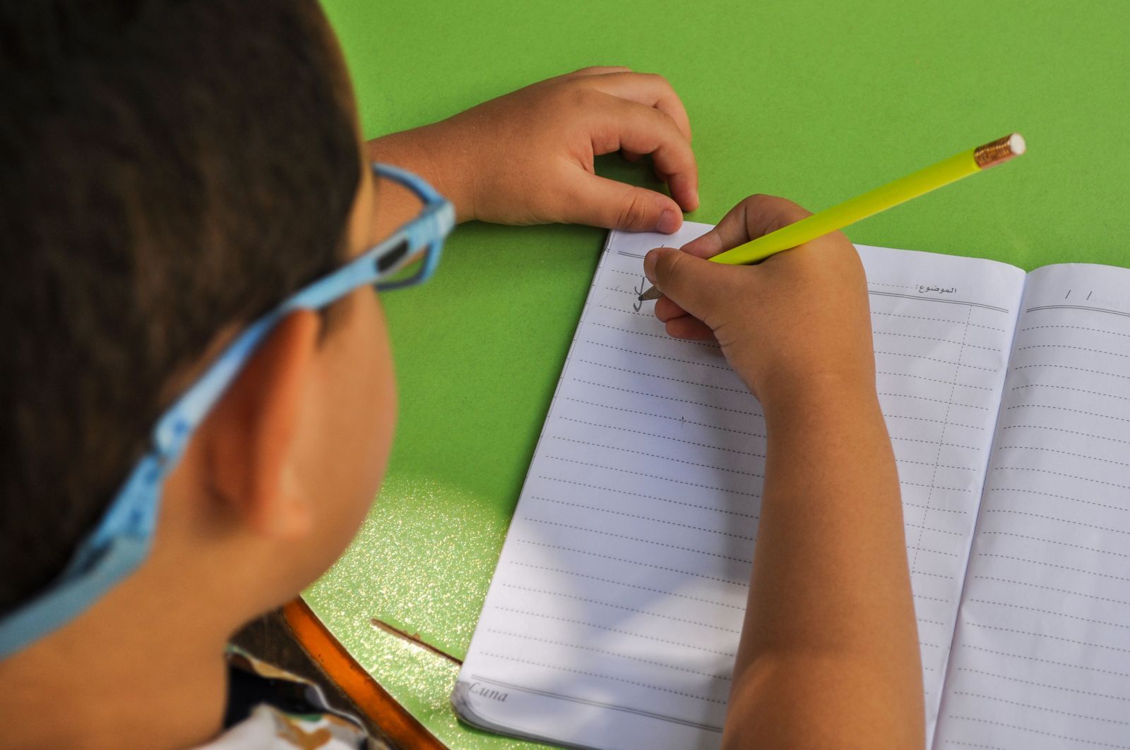 Criança estudando com caderno e lápis
